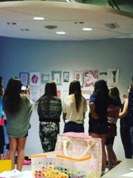 youth standing in a circle looking at zine pages taped to a wall