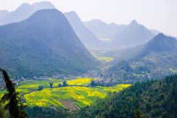 mountains in gray and fields in the valley that are green and lush